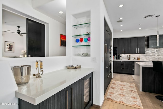 kitchen featuring ceiling fan, kitchen peninsula, beverage cooler, backsplash, and light hardwood / wood-style floors