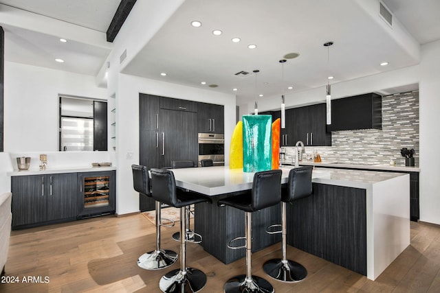 kitchen with pendant lighting, light hardwood / wood-style flooring, tasteful backsplash, and a center island