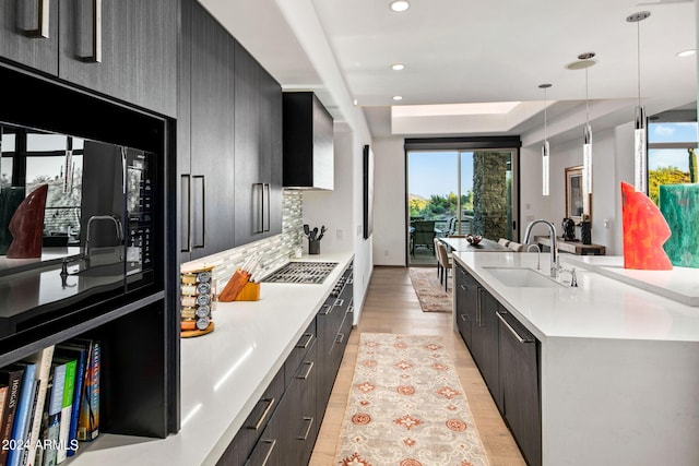 kitchen with light hardwood / wood-style flooring, decorative light fixtures, sink, and a wealth of natural light