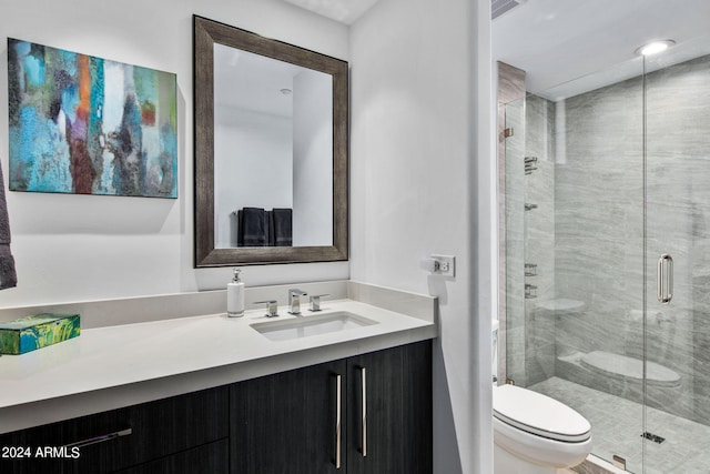 bathroom with vanity, a shower with shower door, and toilet