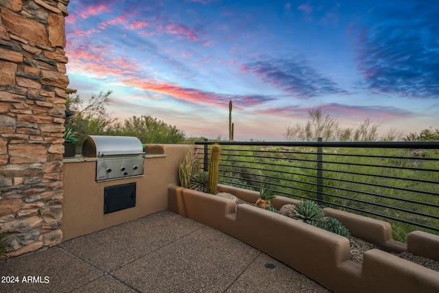 patio terrace at dusk featuring a balcony, area for grilling, and a grill