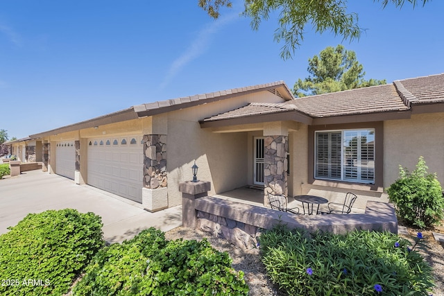 ranch-style house featuring an attached garage, stucco siding, and a tiled roof