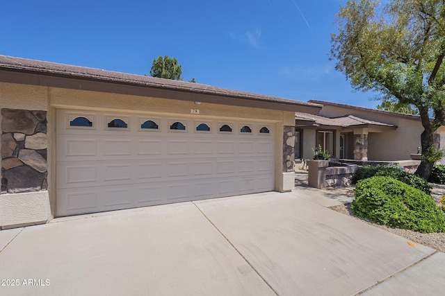 ranch-style house featuring concrete driveway, stone siding, a garage, and stucco siding