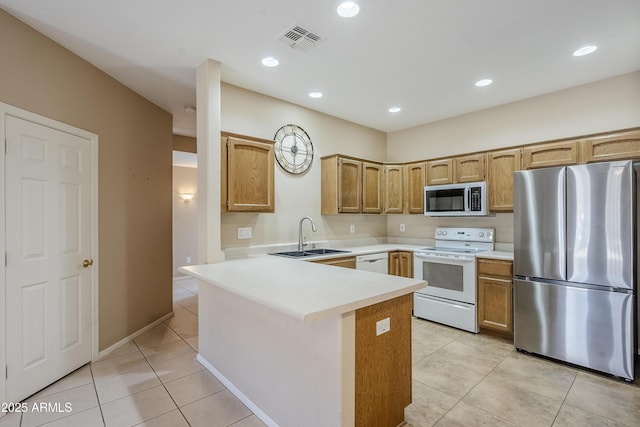 kitchen with appliances with stainless steel finishes, sink, light tile patterned floors, and kitchen peninsula