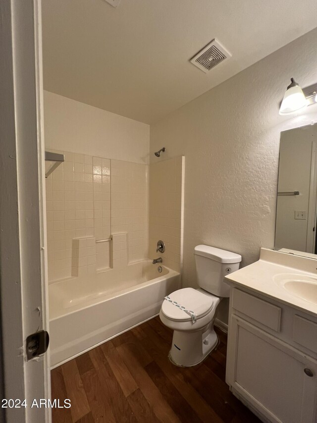 full bathroom with tiled shower / bath, vanity, toilet, and hardwood / wood-style floors