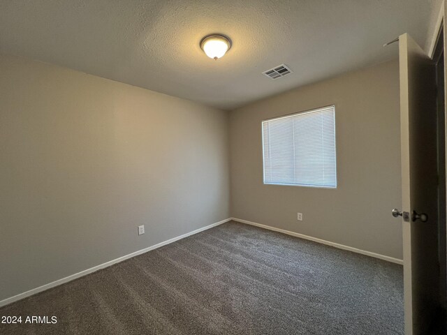 carpeted empty room featuring a textured ceiling