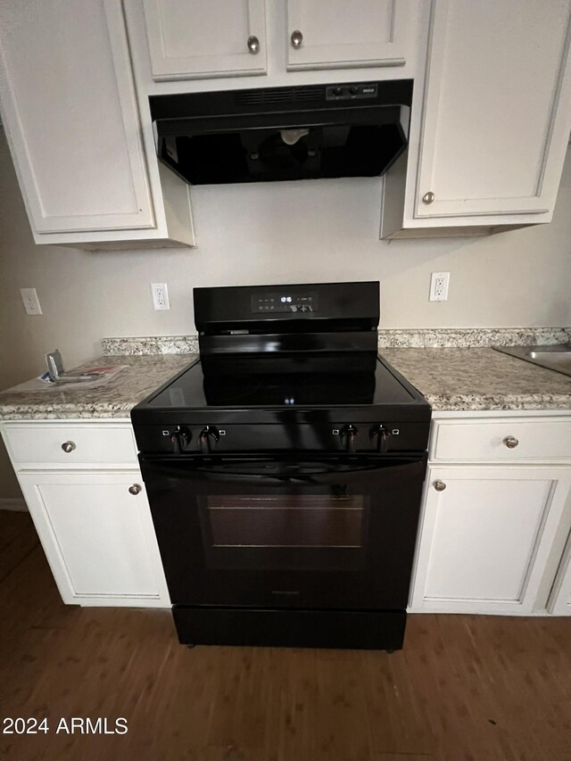 kitchen featuring ventilation hood, white cabinetry, and black stove