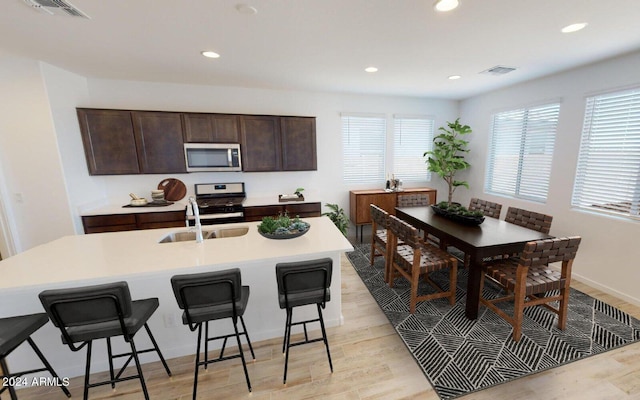 kitchen featuring dark brown cabinets, stainless steel appliances, a kitchen breakfast bar, and visible vents