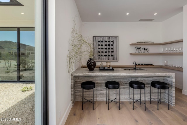 bar featuring indoor wet bar, wood finished floors, a sink, and recessed lighting
