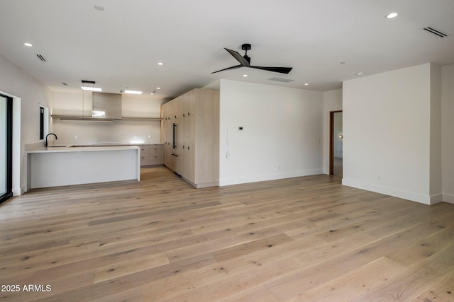 unfurnished living room with a sink, recessed lighting, a ceiling fan, and light wood-style floors
