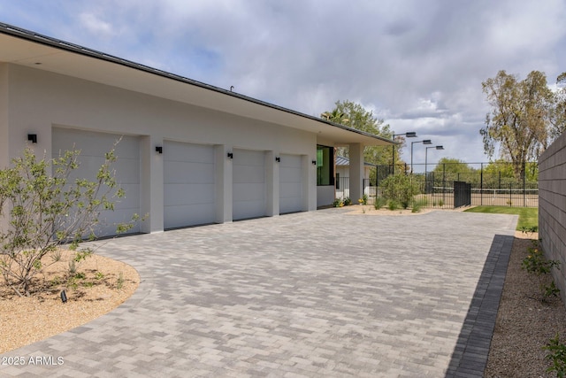 garage featuring fence and decorative driveway