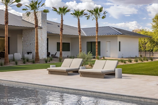 back of property with a patio, a standing seam roof, stucco siding, and metal roof