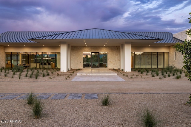 rear view of property with metal roof and stucco siding