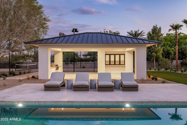 rear view of property featuring a standing seam roof, a patio, and an outdoor pool