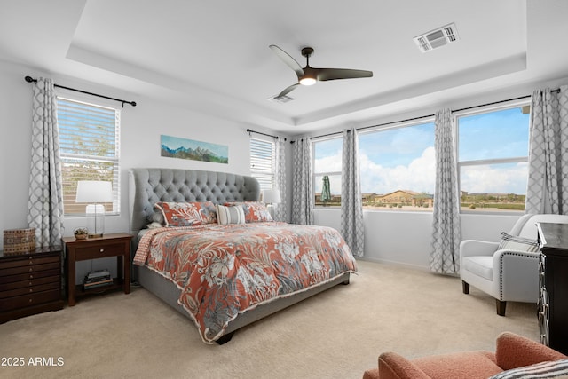 bedroom with carpet flooring, a raised ceiling, ceiling fan, and visible vents