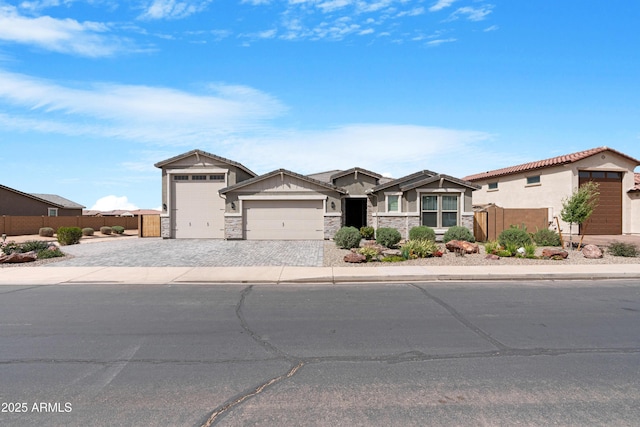 view of front of property featuring stone siding, a garage, fence, and decorative driveway