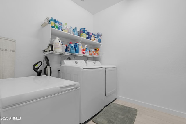 laundry area with baseboards, independent washer and dryer, laundry area, and light wood-type flooring