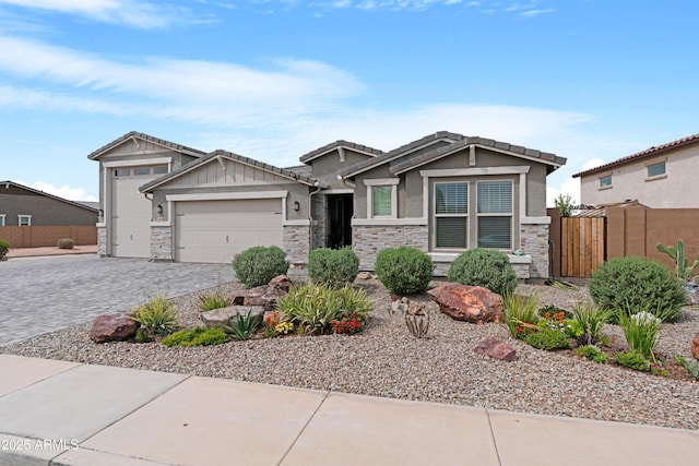 view of front of property with stone siding, fence, decorative driveway, an attached garage, and stucco siding