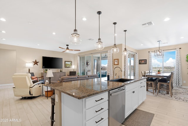 kitchen featuring a sink, an island with sink, light wood finished floors, visible vents, and dishwasher