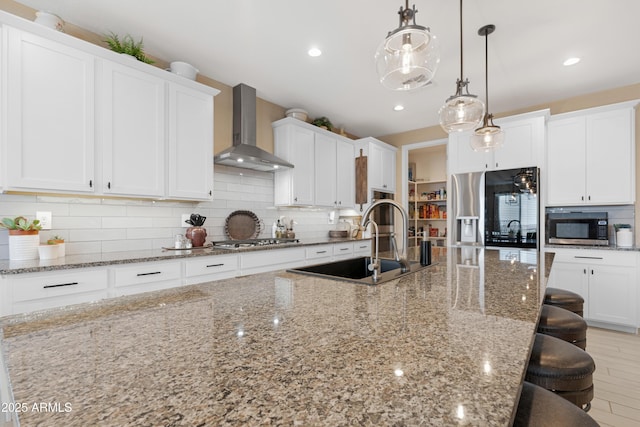 kitchen featuring tasteful backsplash, stainless steel appliances, a breakfast bar, a sink, and wall chimney exhaust hood