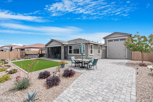 back of house with decorative driveway, a patio, fence private yard, stucco siding, and a yard