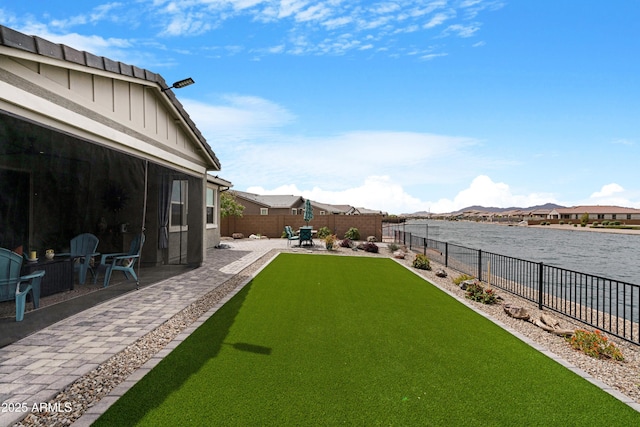 view of yard featuring a water and mountain view, a fenced backyard, and a patio area