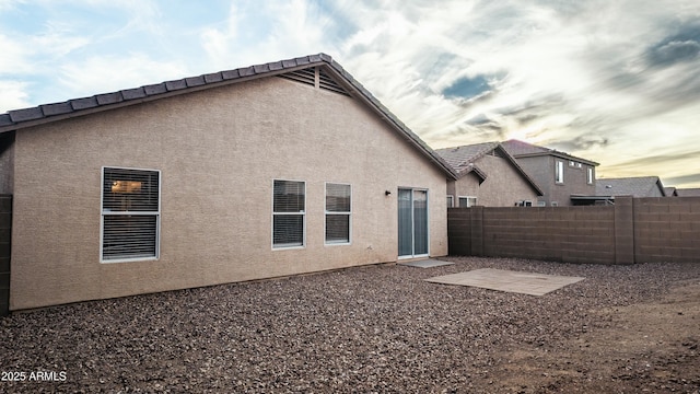 back house at dusk with a patio area