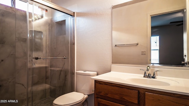 bathroom featuring vanity, a shower with door, and toilet