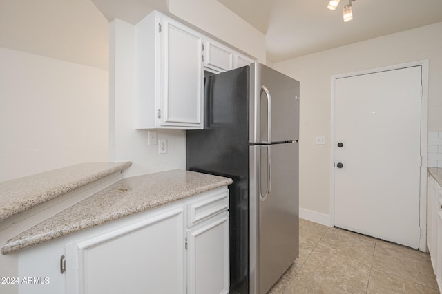 kitchen with stainless steel refrigerator, light tile patterned floors, and white cabinetry