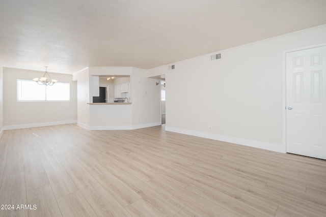 unfurnished living room with light wood-type flooring and a notable chandelier