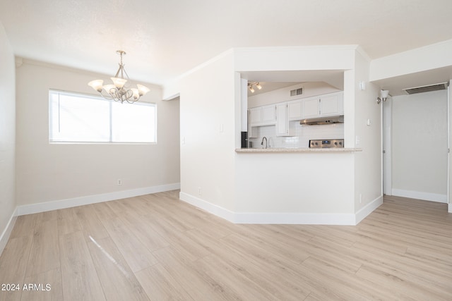 unfurnished living room featuring crown molding, light hardwood / wood-style flooring, sink, and a notable chandelier