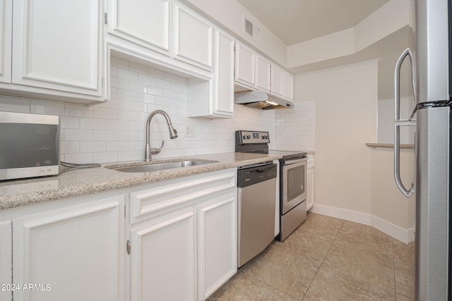 kitchen featuring white cabinets, backsplash, appliances with stainless steel finishes, light stone counters, and sink