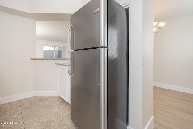 kitchen featuring stainless steel fridge, white cabinetry, and light hardwood / wood-style flooring