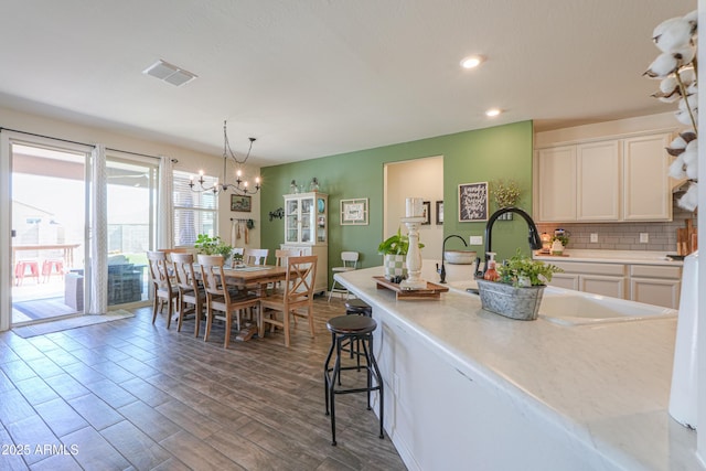 kitchen featuring visible vents, light countertops, decorative backsplash, dark wood-style floors, and white cabinets