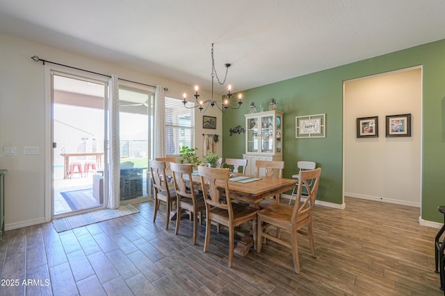 dining area featuring an inviting chandelier, baseboards, and wood finished floors