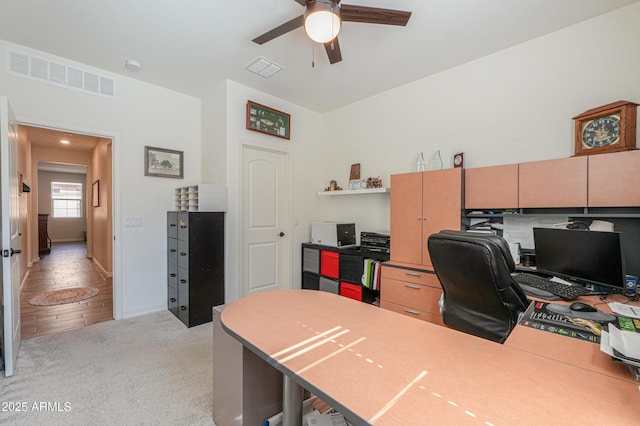 office area featuring ceiling fan, baseboards, visible vents, and light carpet