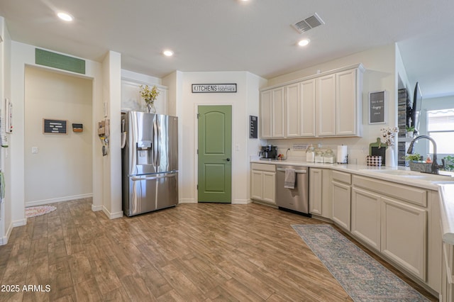 kitchen featuring visible vents, stainless steel appliances, light wood-type flooring, and a sink