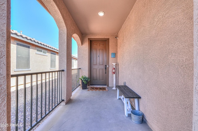 doorway to property featuring a tiled roof, a balcony, and stucco siding