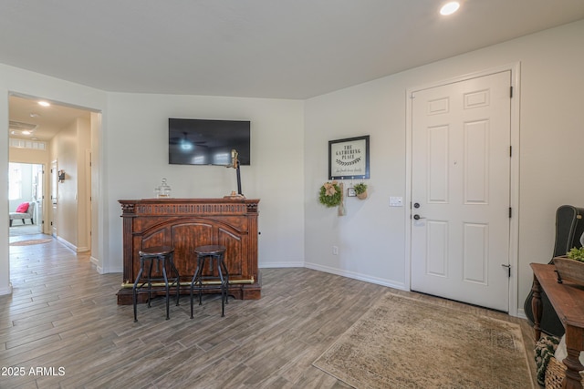 living area featuring a bar, baseboards, and wood finished floors