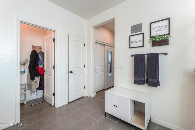 mudroom with visible vents, baseboards, and dark tile patterned flooring