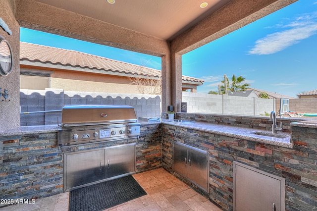 view of patio featuring area for grilling, a grill, a fenced backyard, and a sink