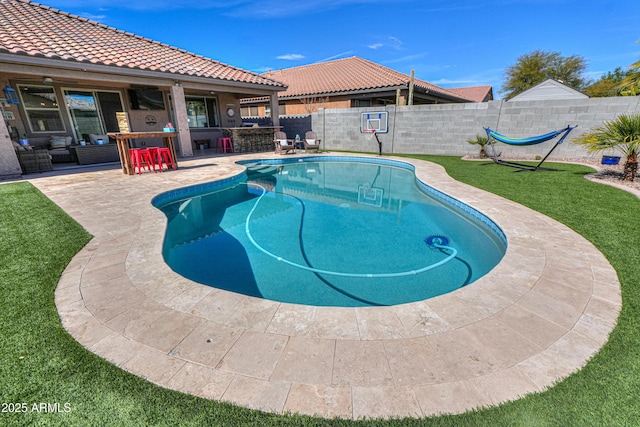 view of pool with an outdoor living space, a yard, a fenced backyard, a patio area, and outdoor dry bar