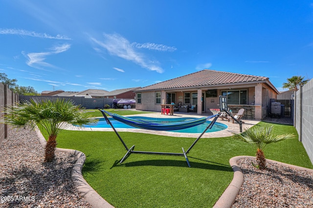 rear view of property featuring a fenced in pool, a tiled roof, stucco siding, a fenced backyard, and a patio