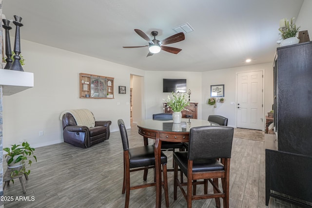 dining space with a ceiling fan, wood finished floors, visible vents, and baseboards