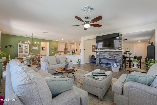 living area featuring visible vents, recessed lighting, ceiling fan with notable chandelier, a fireplace, and wood finished floors