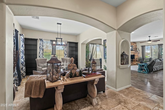 891 W Palo Brea Dr, Litchfield Park, AZ 85340 - dining space with ceiling fan with notable chandelier, baseboards, a fireplace, and plenty of natural light