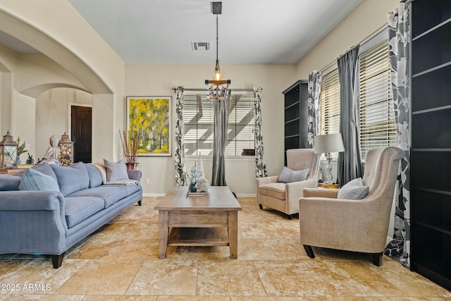 891 W Palo Brea Dr, Litchfield Park, AZ 85340 - living room featuring an inviting chandelier, visible vents, stone finish flooring, baseboards, and arched walkways