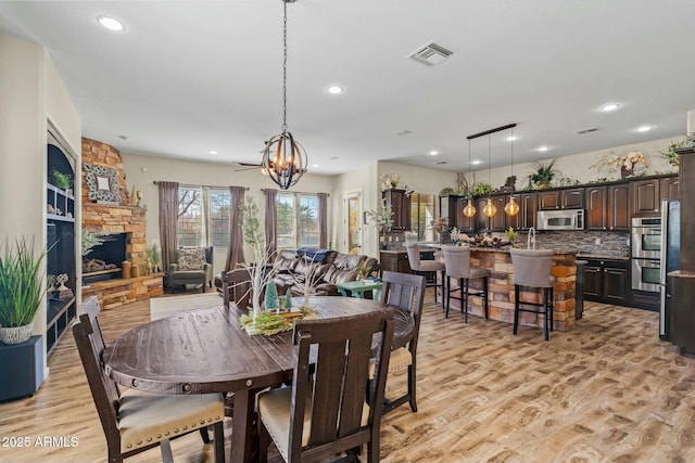 891 W Palo Brea Dr, Litchfield Park, AZ 85340 - dining space featuring visible vents, a chandelier, light wood-style floors, recessed lighting, and a fireplace