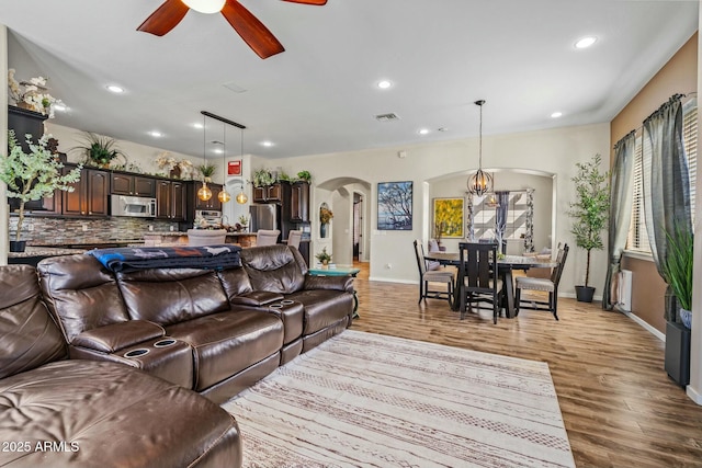 891 W Palo Brea Dr, Litchfield Park, AZ 85340 - living area with light wood-style flooring, visible vents, arched walkways, ceiling fan with notable chandelier, and recessed lighting