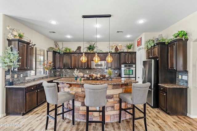 891 W Palo Brea Dr, Litchfield Park, AZ 85340 - kitchen with dark brown cabinets, a kitchen island, decorative light fixtures, and stainless steel appliances